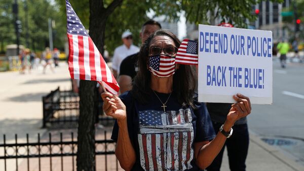 A woman holds a flag and placard as she attends a Back the Blue rally in support and solidarity with law enforcement, in Chicago, Illinois, U.S., July 25, 2020. - Sputnik International