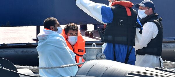 Migrants (L), believed to have been picked up from boats in the Channel, are given instructions by Border Force officials on-board Coastal patrol vessel HMC Hunter, in the port of Dover, on the south-east coast of England on 9 August 2020.  - Sputnik International