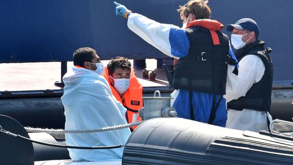 Migrants (L), believed to have been picked up from boats in the Channel, are given instructions by Border Force officials on-board Coastal patrol vessel HMC Hunter, in the port of Dover, on the south-east coast of England on 9 August 2020.  - Sputnik International