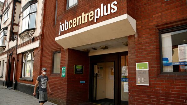 A man wearing a protective face mask walks by a Jobcentre Plus office, following the outbreak of the coronavirus disease (COVID-19), in Chester, Britain August 11, 2020 - Sputnik International
