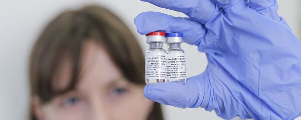 In this handout photo released by Russian Direct Investment Fund and the Gamaleya Scientific Research Institute of Epidemiology and Microbiology, a scientist holds phials of the world's first coronavirus vaccine registered in Russia, in Moscow, Russia.  - Sputnik International