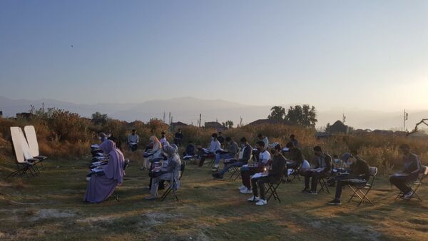 Students make space for themselves on the unkept ground with tall grasses and bushes in the open-air classroom in Srinagar - Sputnik International
