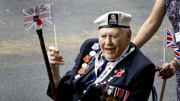 A veteran waves a flag during the parade to commemorate VJ day, as it passes along Whitehall in London, Saturday, Aug. 15, 2015. The parade, comprised of veterans of the Far East Campaign, their families and descendants, led by Pipes and Drums drawn from the Army, was to mark the 70th anniversary of the victory over Japan during World War II. - Sputnik International