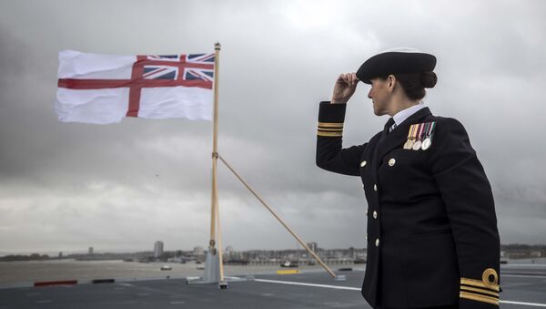 A naval officer looks up at the fluttering White ensign flag hoisted at the stern during the Commissioning Ceremony for the Royal Navy aircraft carrier HMS Queen Elizabeth at HM Naval Base in Portsmouth, southern England on December 7, 2017. - Sputnik International