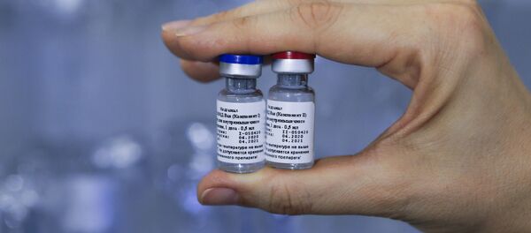 In this handout photo released by Russian Direct Investment Fund and the Gamaleya Scientific Research Institute of Epidemiology and Microbiology, a scientist holds phials of the world's first coronavirus vaccine registered in Russia, in Moscow, Russia - Sputnik International