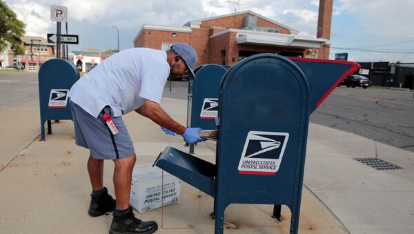 A United States Postal Service (USPS) worker handles the mail in a drop-off box behind a post office in Oak Park, Michigan, U.S.  August 17, 2020 - Sputnik International