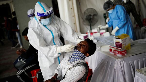 A healthcare worker wearing personal protective equipment (PPE) takes a swab from a migrant worker, who returned to Delhi from his native state, for a rapid antigen test at a bus terminal, amidst the coronavirus disease (COVID-19) outbreak in New Delhi, India, August 17, 2020 - Sputnik International