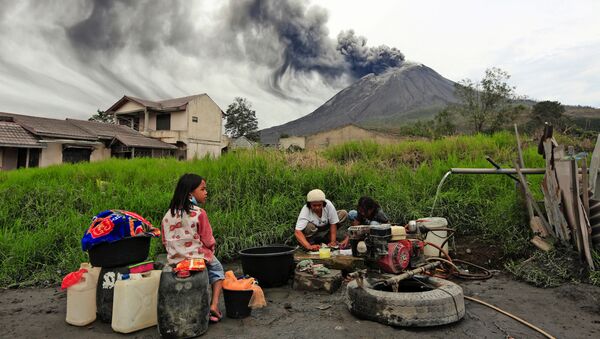 Villagers do their laundry as Mount Sinabung spews volcanic materials during an eruption, in Karo, North Sumatra, Indonesia Friday, Aug. 14, 2020.  - Sputnik International