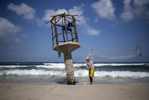 A Palestinian fisherman cleans up his fishing net after the Israeli decision to close Gaza's fishing zone, on the beach in Gaza City, Tuesday, 18 August 2020.  - Sputnik International