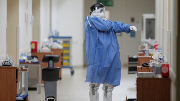 A healthcare worker puts on his protective suit while using a robot to carry out consultations with patients suffering from the coronavirus disease (COVID-19), at NOVA hospital in Monterrey, Mexico August 18, 2020.  - Sputnik International