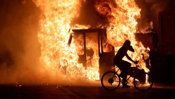 A man on a bike rides past a city truck on fire outside the Kenosha County Courthouse in Kenosha, Wisconsin, U.S., during protests following the police shooting of Black man Jacob Blake August 23, 2020. - Sputnik International