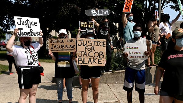 People hold placards as they gather for a protest outside the Kenosha County Courthouse after a Black man, identified as Jacob Blake, was shot several times by police last night in Kenosha, Wisconsin, U.S. August 24, 2020. Picture taken August 24, 2020 - Sputnik International