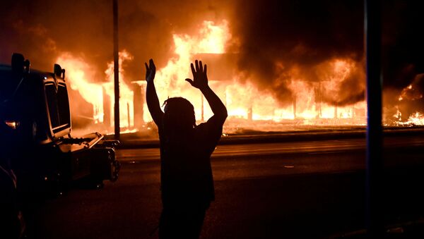 A man walks by an armoured vehicle as B&L Office Furniture burns in the background as protests turn to fires after a Black man, identified as Jacob Blake, was shot several times by police last night in Kenosha, Wisconsin, U.S. August 24, 2020 - Sputnik International