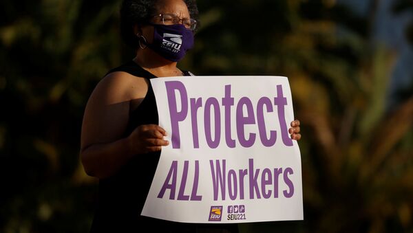 Social Worker Iris Trammel hold a sign during a vigil to honor San Diego county employees who have lost their lives to the coronavirus (COVID-19) while working the frontline of the pandemic in San Diego, California August 24, 2020 - Sputnik International