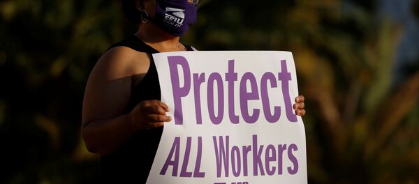 Social Worker Iris Trammel hold a sign during a vigil to honor San Diego county employees who have lost their lives to the coronavirus (COVID-19) while working the frontline of the pandemic in San Diego, California August 24, 2020 - Sputnik International