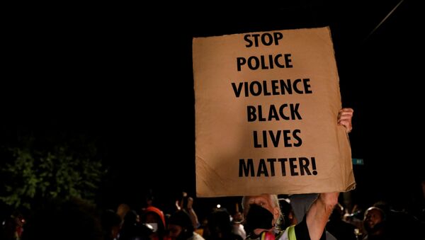 A man holds up a sign as demonstrators take part in a protest following the police shooting of Jacob Blake, a Black man, in Kenosha, Wisconsin, U.S. August 26, 2020.  - Sputnik International