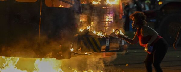 A protester lights a cigarette on a garbage truck that was set on fire during protests late Monday, Aug. 24, 2020, in Kenosha, Wis., sparked by the shooting of Jacob Blake by a Kenosha Police officer a day earlier. A protester lights a cigarette on a garbage truck that was set on fire during protests late Monday, Aug. 24, 2020, in Kenosha, Wis., sparked by the shooting of Jacob Blake by a Kenosha Police officer a day earlier. - Sputnik International