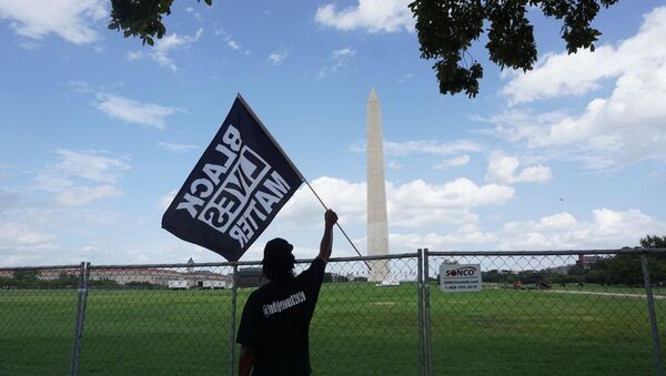 A participant of the rally commemorating the 57th anniversary of the March on Washington is seen holding a Black Lives Matter flag in front of the Washington Monument. - Sputnik International