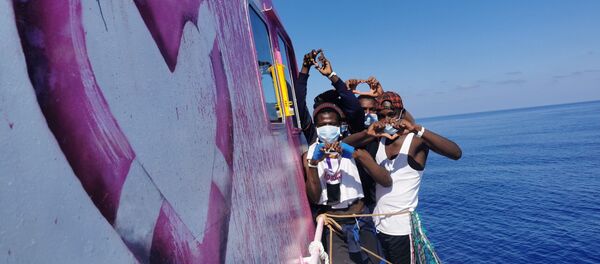 In this undated handout photo people pose for a photo after being rescued by the Louise Michel, a migrants search and rescue ship operating in the Mediterranean and financed by British street artist Banksy, at sea. - Sputnik International