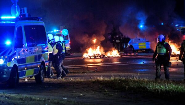 Police officers walk near the burning tyres and pallets during a riot in the Rosengard neighbourhood of Malmo, Sweden August 28, 2020 - Sputnik International