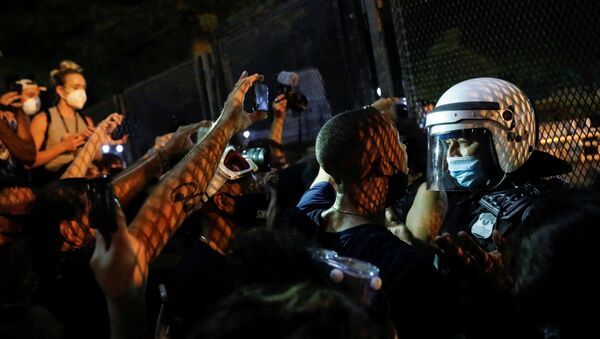 Demonstrators face off with a security officer near a fence around the White House during a protest  in Washington, U.S. August 27, 2020 - Sputnik International