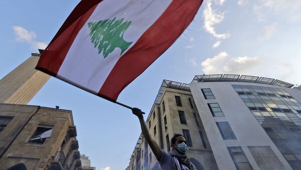 A Lebanese protester waves a national flag amid clashes with security forces in central Beirut on August 10, 2020.  - Sputnik International