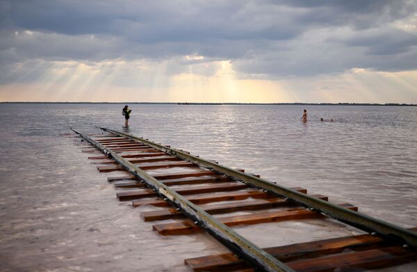 People rest in the Burlinskoye lake in Russia's Altay region. A railway line is needed to remove salt which is being extracted from the lake. - Sputnik International