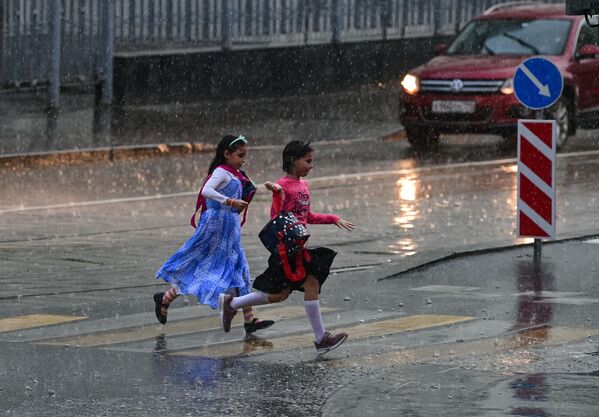 Girls run across the road during the rain in Moscow.  - Sputnik International