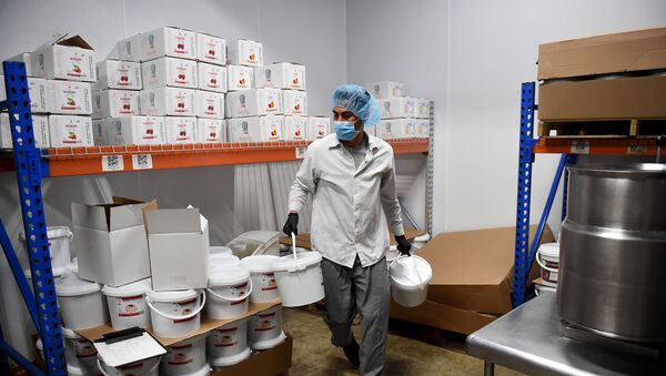 An employee wearing a face mask prepares a shipment of blueberry filing at PastryStar on May 4, 2020, in Laurel, Maryland. - At the Picou family's factory in Laurel, Maryland outside the US capital, the only workshop that is buzzing is usually reserved for making jams for baking. Now, it's churning out hand sanitizer. Before the coronavirus pandemic, PastryStar -- founded stateside in 1986 -- made a wide array of products for high-end baking, supplying everything from chic restaurants to cruise lines. - Sputnik International