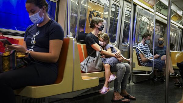 A child rests on a subway car while riders wear protective masks due to COVID-19 concerns, Monday, Aug. 17, 2020, in New York. - Sputnik International