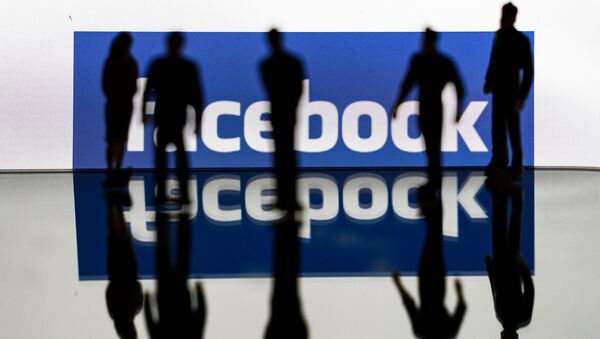 (FILES) In this file photo taken on February 14, 2020 silhouettes are seen in front of the logo of US social media Facebook in Brussels - Sputnik International