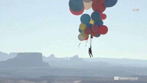 Extreme performer David Blaine hangs with a parachute under a cluster of balloons during a stunt to fly thousands of feet into the air in a still image from video taken over Page, Arizona, U.S. September 2, 2020 - Sputnik International