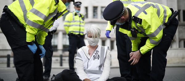 Police officers talk to an activist from the climate protest group Extinction Rebellion who is sat in the road in Parliament Square in central London on September 2, 2020 on the second day of the group's new series of 'mass rebellions'. - Sputnik International