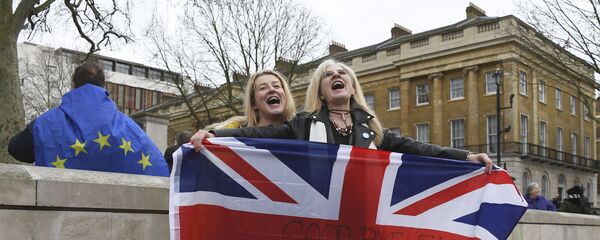 Brexit supporters hold the Union Jack with a text reading Goodbye EU as they celebrate next to a person wearing the EU flag in London, Friday, Jan. 31, 2020 - Sputnik International