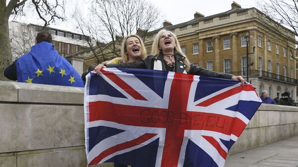 Brexit supporters hold the Union Jack with a text reading Goodbye EU as they celebrate next to a person wearing the EU flag in London, Friday, Jan. 31, 2020 - Sputnik International