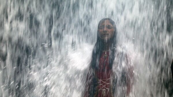 A woman stands under a waterfall as a lake overflows due to heavy rainfall in Mumbai, India August 29, 2020 - Sputnik International