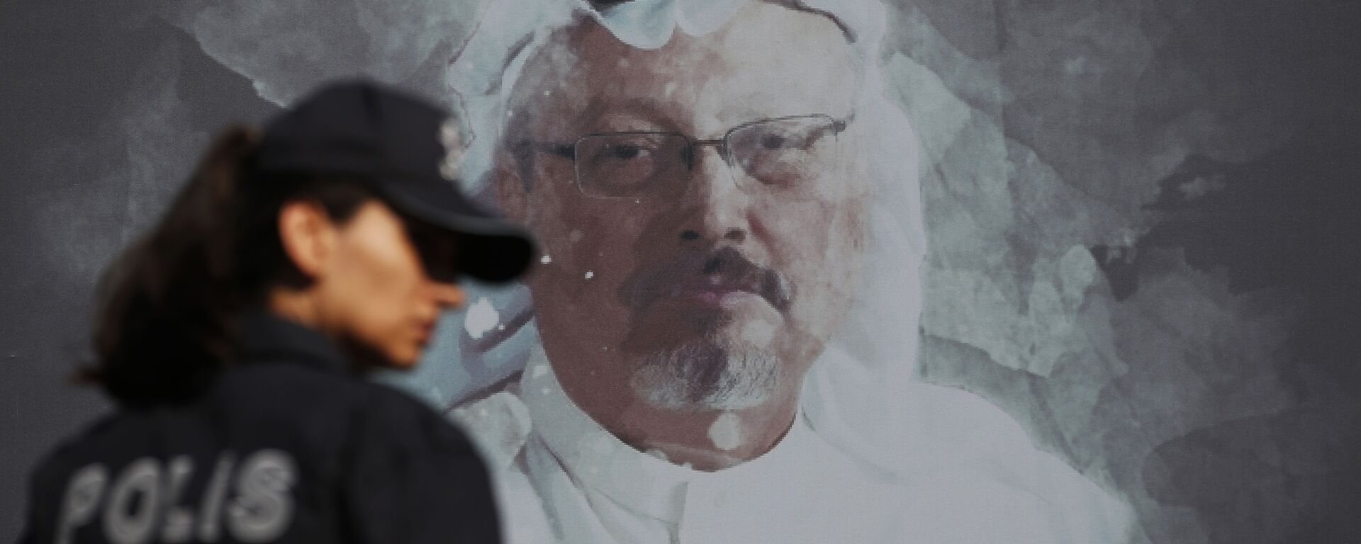 A Turkish police officer walks past a picture of slain Saudi journalist Jamal Khashoggi prior to a ceremony, near the Saudi Arabia consulate in Istanbul, marking the one-year anniversary of his death, 2 October 2019 - Sputnik International, 1920, 24.02.2021