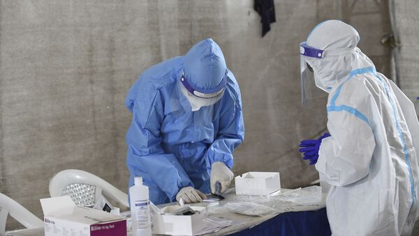 Health workers wearing  Personal Protective Equiment (PPE) kits work on the collected swab samples for the Covid-19 coronavirus at a testing camp in Sanathal, on the outskirts of Ahmedabad on August 30, 2020. - Sputnik International