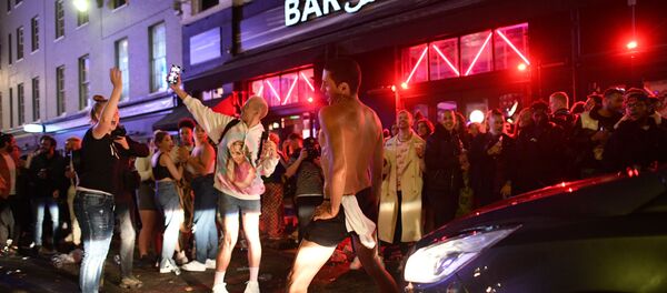 A car tries to drive down a street filled with revellers drinking in London's Soho neighbourhood on 4 July 2020, after the police re-opened the road at 23:00 as COVID-19 pandemic-related restrictions were eased. A car tries to drive down a street filled with revellers drinking in London's Soho neighbourhood on 4 July 2020, after the police re-opened the road at 23:00 as COVID-19 pandemic-related restrictions were eased. - Sputnik International