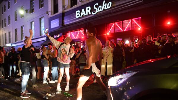 A car tries to drive along a street filled with revellers drinking in the Soho area of London on 4 July 2020, after the police re-opened the road at 23:00 as COVID-19 restrictions were eased over the summer. - Sputnik International