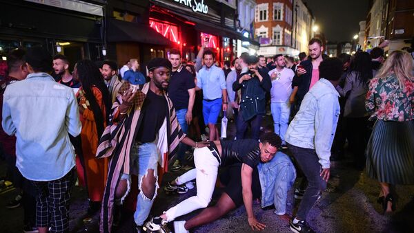 Revellers dance in the street in the Soho area of London on July 4, 2020, following a further easing of restrictions to allow pubs and restaurants to open during the novel coronavirus COVID-19 pandemic.  - Sputnik International