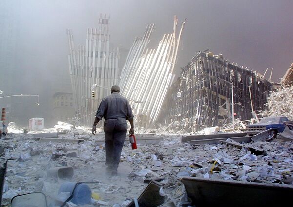 A man with a fire extinguisher walks through rubble after the collapse of the first World Trade Center Tower on 11 September 2001, in New York - Sputnik International