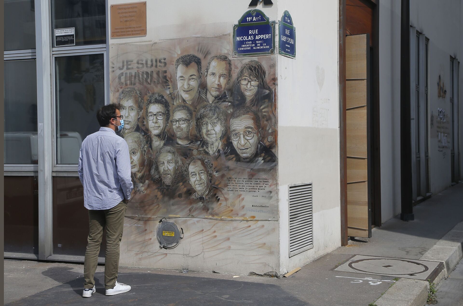 A man wearing a protective face mask as a precaution against the coronavirus looks on a painting by French street artist Christian Guemy, a.k.a. 'C215' in Paris Wednesday, Sept. 2, 2020, in tribute to the members of the satirical newspaper Charlie Hebdo attack by jihadist gunmen in January 2015. Thirteen men and a woman go on trial Wednesday over the 2015 attacks against a satirical newspaper and a kosher supermarket in Paris that marked the beginning of a wave of violence by the Islamic State group in Europe. Seventeen people and all three gunmen died during the three days of attacks in January 2015 - Sputnik International, 1920, 07.09.2021