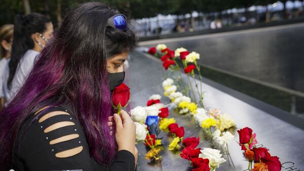 A mourner kisses a rose through her face mask before placing it in a name cut-out of the deceased at the National September 11 Memorial and Museum, Friday, Sept. 11, 2020, in New York - Sputnik International