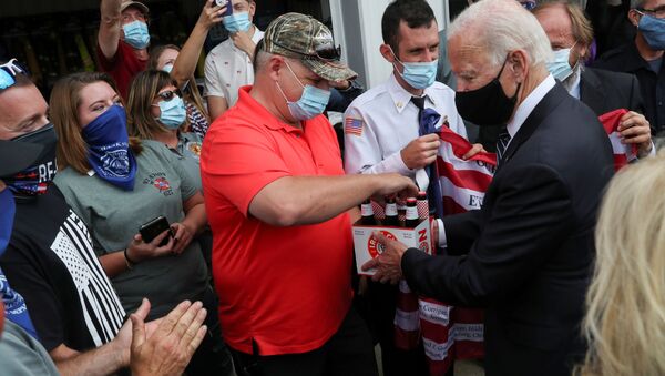 Democratic U.S. presidential nominee and former Vice President Joe Biden hands over a six pack of beer to Frank Barta that he said he brought for firefighters after promising to bring beer during a previous visit to Shanksville fire station number 627 long ago, as Biden stopped at the fire hall after visiting the nearby Flight 93 National Memorial to those killed when hijacked Flight 93 crashed into an open field on September 11, 2001, in Shanksville, Pennsylvania, September 11, 2020.  - Sputnik International