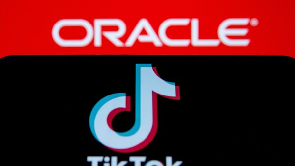 A smartphone with the Tik Tok logo is seen in front of a displayed Oracle logo in this illustration taken, Septemeber 14, 2020. REUTERS/Dado Ruvic/Illustration - Sputnik International