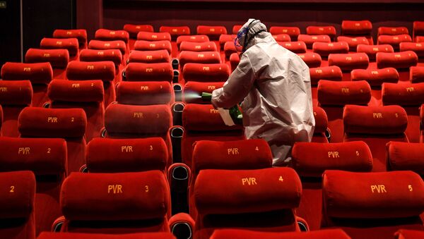 A PVR Cinemas employee wearing a Personal Protective Equipment (PPE) suit sanitises a cinema hall as part of preparations for a possible reopening amid concerns over the spread of the COVID-19 coronavirus, in New Delhi on 31 July 2020. - Sputnik International