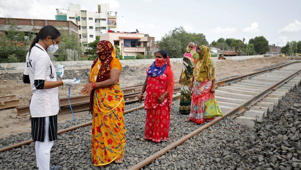 A healthcare worker puts a pulse oximeter on a woman's finger to check her oxygen level during survey for the coronavirus disease (COVID-19) at the construction site of a railway track, amidst the spread of the disease in Babla village on the outskirts of Ahmedabad, India, 15 September 2020 - Sputnik International