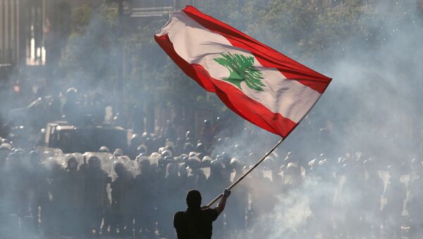 A demonstrator waves the Lebanese flag in front of riot police - Sputnik International