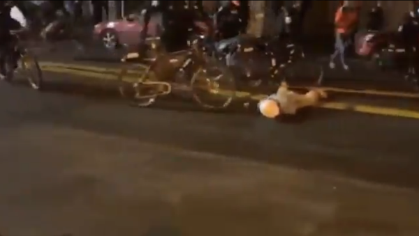 Screenshot from a video showing a police officer in Seattle walking his bike across the head of the man lying on the ground - Sputnik International